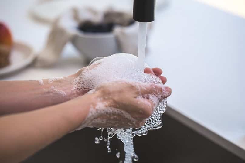 ידיים מקציפות סבון ומים בו זמנית מתחת למי ברז זורמים מדמה ניקיון
