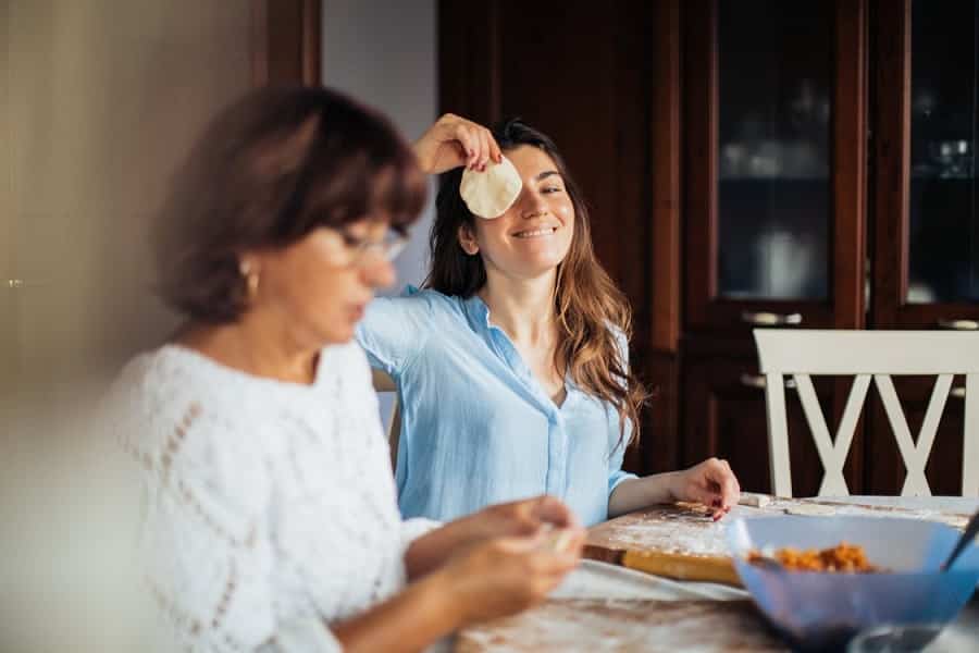 אמא ובת מכינות כיסונים ביחד והבת עושה פרצופים מצחיקים למצלמה