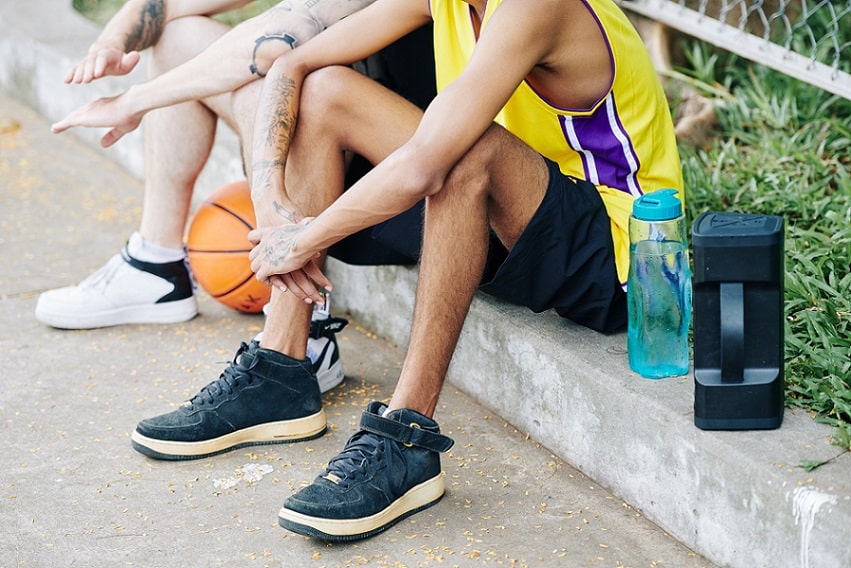 שחקני כדורסל רחוב עם נעלי כדורסל יושבים על הבטון בין המשחקים