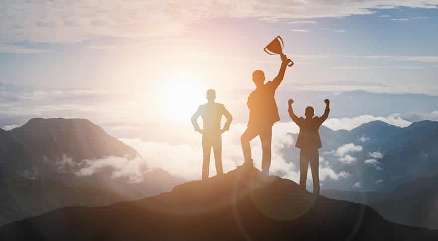 3 אנשים עומדים על פסגה של הר ואחד מחזיק גביע
