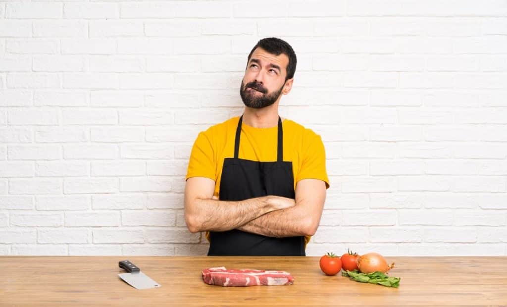 בחור יושב מול דלפק עם ירקות בשר וסכין שואל שאלה