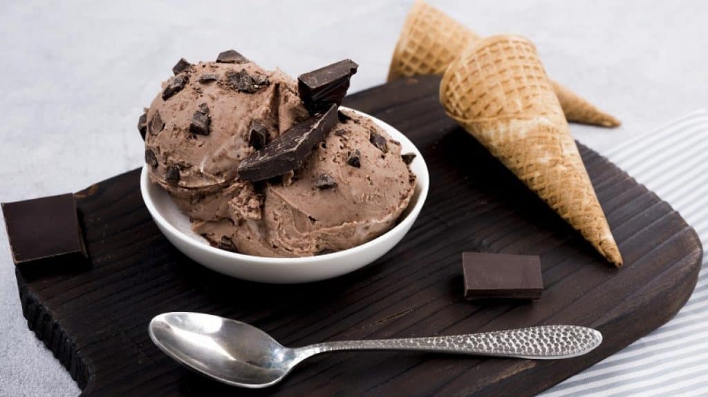 שני גביעי גלידה קערה וכפית על צלחת שחורה עם שוקולד