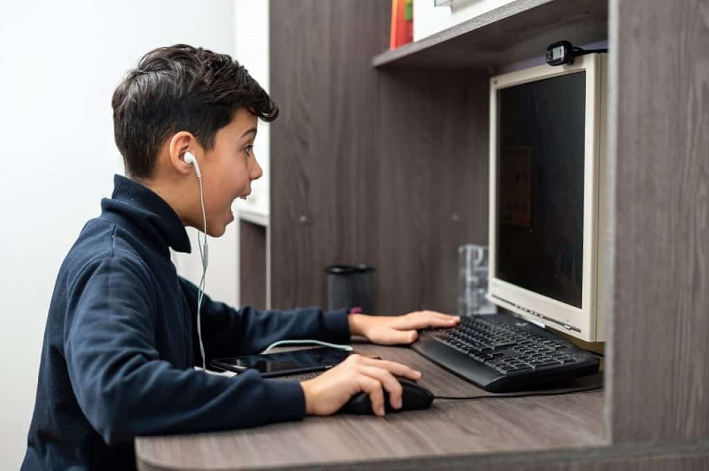 ילד עם חולצת גולף משחק במחשב עם אוזניות