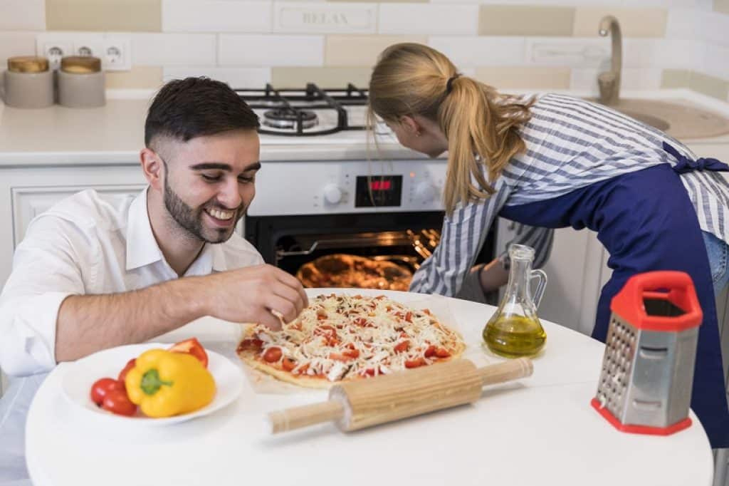 בעל ואישה מכינים ביחד פיצה לארוחת ערב