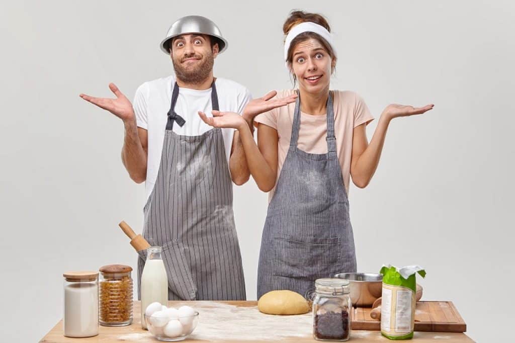 גבר ואישה באמצע בישולים עם הבעת שאלה על הפנים