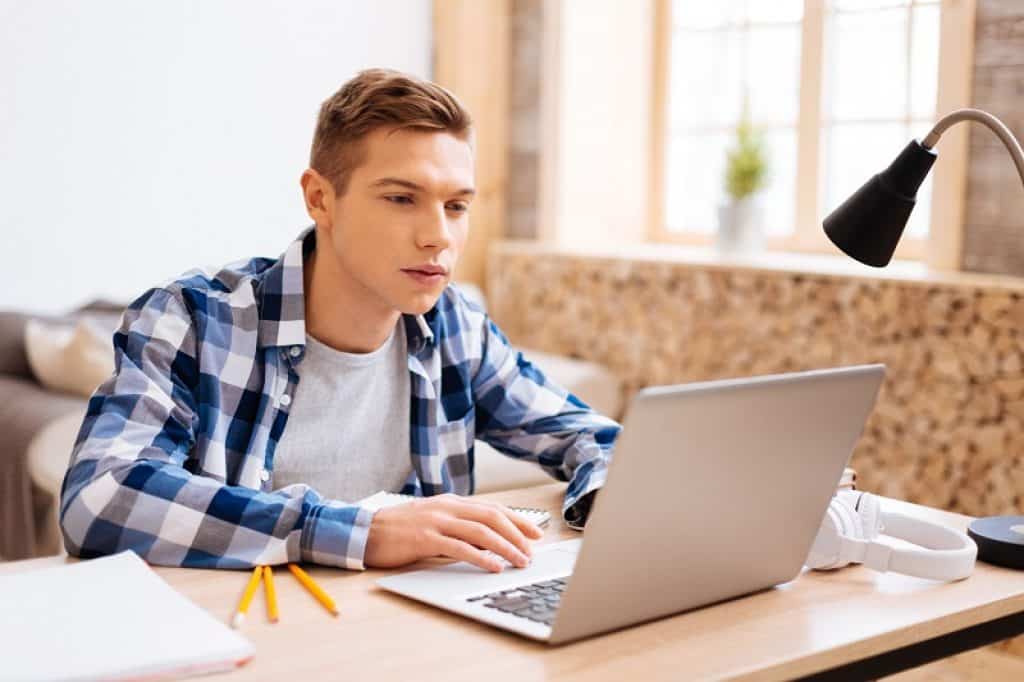 סטודנט עם חולצה משובצת משתמש במחשב על שולחן כתיבה