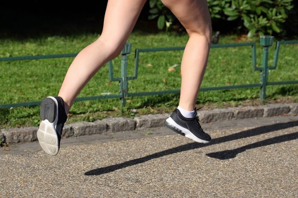 רגליים של בחורה עם נעלי ריצה בזמן קפיצה באוויר