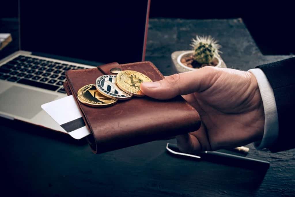 יד של גבר בחליפה מחזיקה ארנק עם מטבעות דיגיטליים