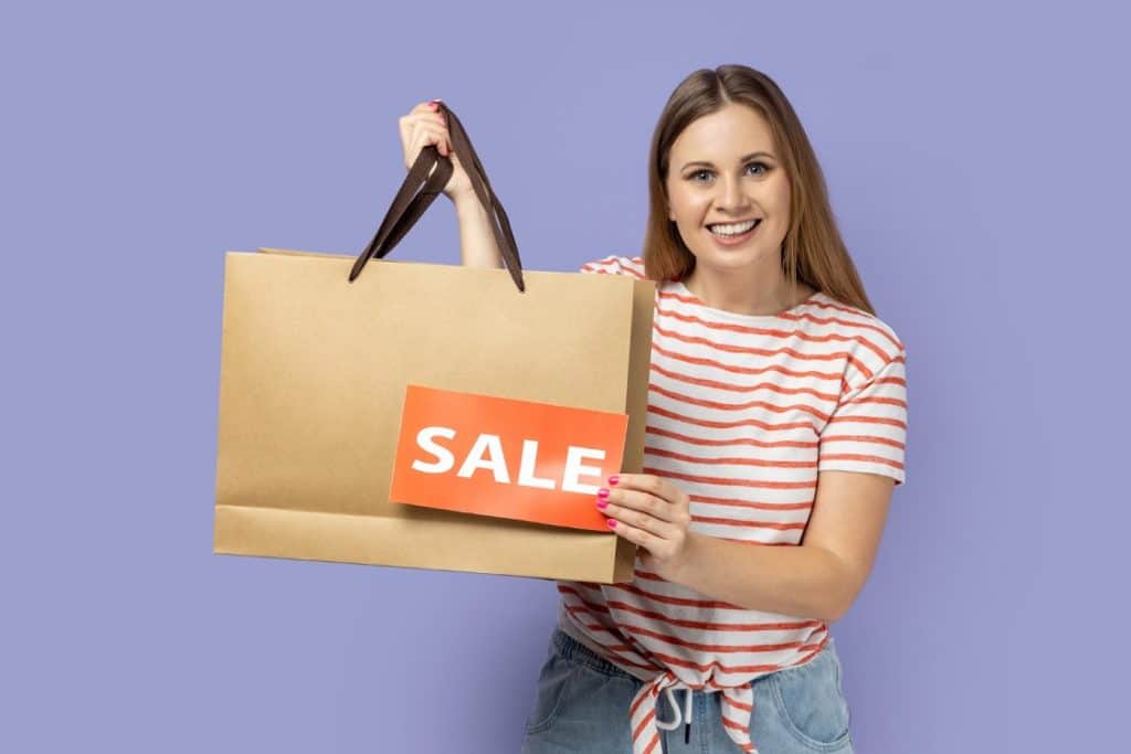 אישה מחזיקה תיק עם קניות שקנתה בהנחה
