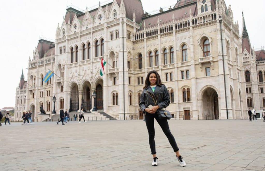 בחורה מטיילת מחייכת עומדת ליד ארמון בבודפשט