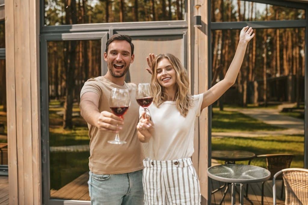 גבר ואישה מחייכים ומאושרים מחזיקים כוסות יין אדום 