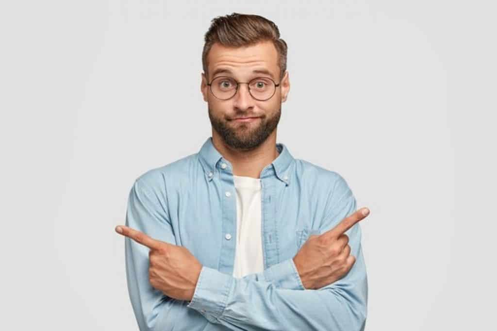 איש עם חולצה מכופתרת ומשקפיים מצביע לשני כיוונים ומתלבט רקע לבן