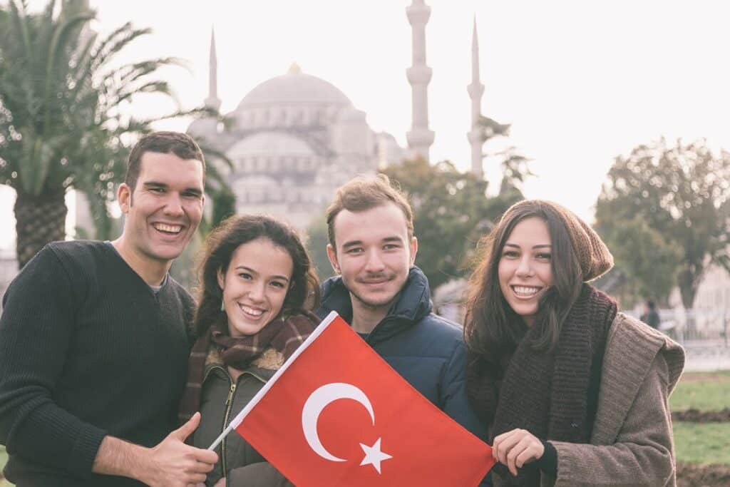 קבוצת חברים מחייכים ומצטלמים עם דגל טורקיה וברקע ארמון עתיק