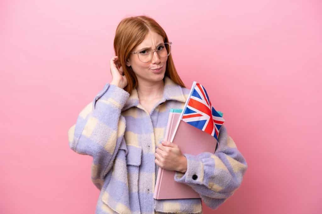 בחורה עם משקפיים ספרים ודגל אנגליה מבט חושב רקע ורוד