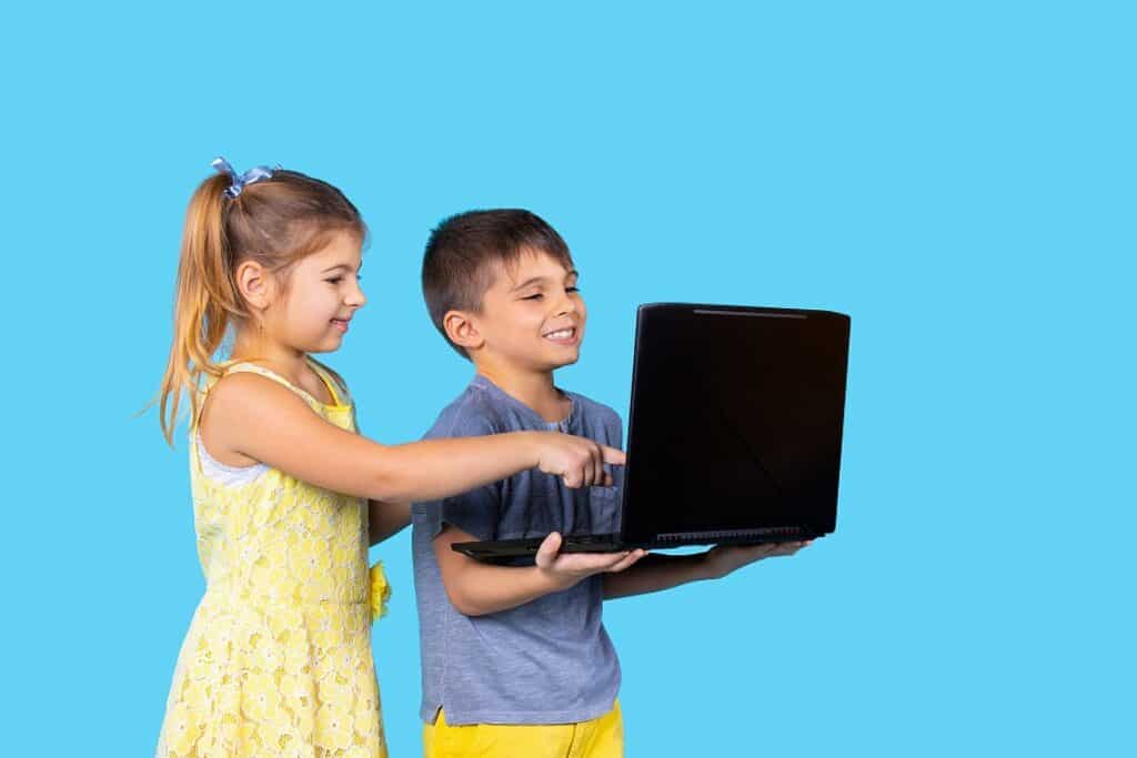ילד וילדה מחזיקים מחשב נייד ומסתכלים עליו רקע תכלת