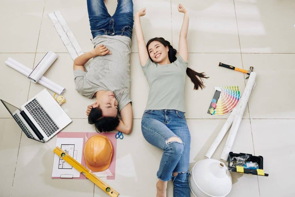 בחור ובחורה שוכבים על הרצפה ומחייכים וסביבם מוצרים לעיצוב פנים