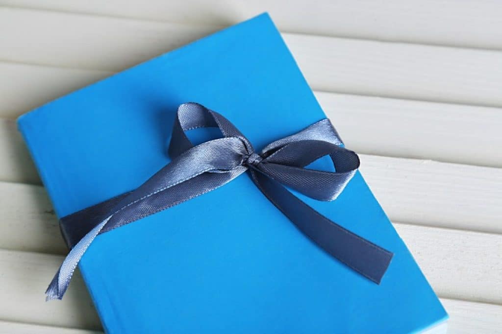 ספר כחול עטוף בסרט כחול כמתנה ספר מומלץ רקע בהיר
