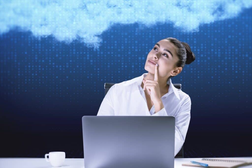 בחורה עם מחשב נייד יושבת וחושבת עם יד על הסנטר רקע כחול