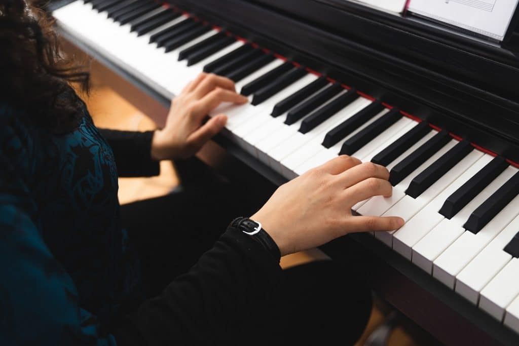 ידיים של בחורה מנגנות בעדינות על פסנתר חשמלי 