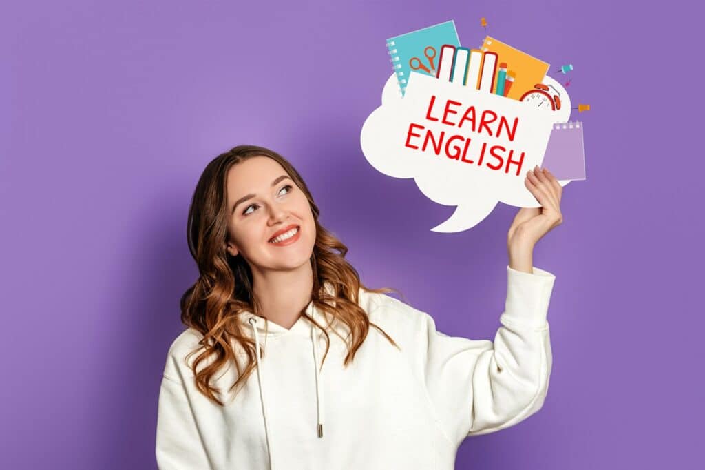 בחורה בחולצה לבנה מחזיקה שלט לומדים אנגלית ומחייכת רקע סגול 