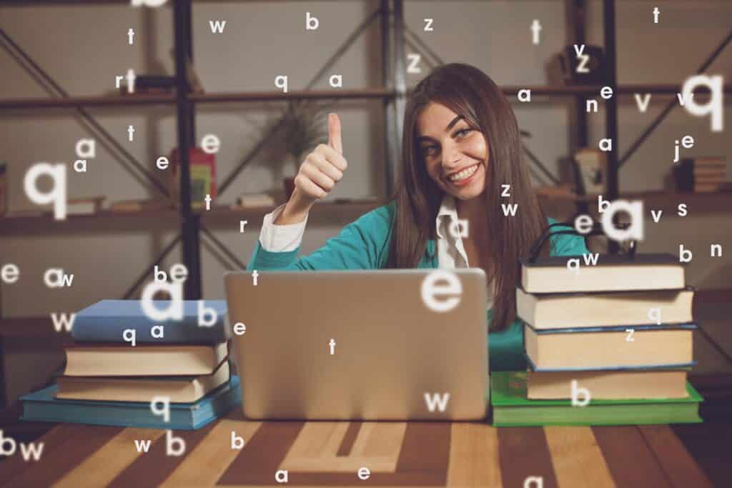 בחורה יושבת מול מחשב וספרים מחייכת ומרימה אגודל באוויר