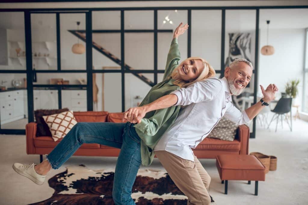 גבר ואישה מחייכים וצוחקים ביחד בסלון ברקע בית מעוצב