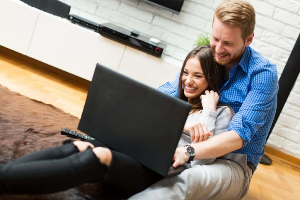 זוג יושב על הרצפה וגולש באינטרנט עם חיוך
